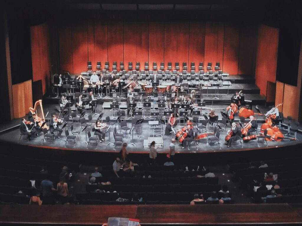Capture of a live orchestra setup in an indoor concert hall with audience seated.